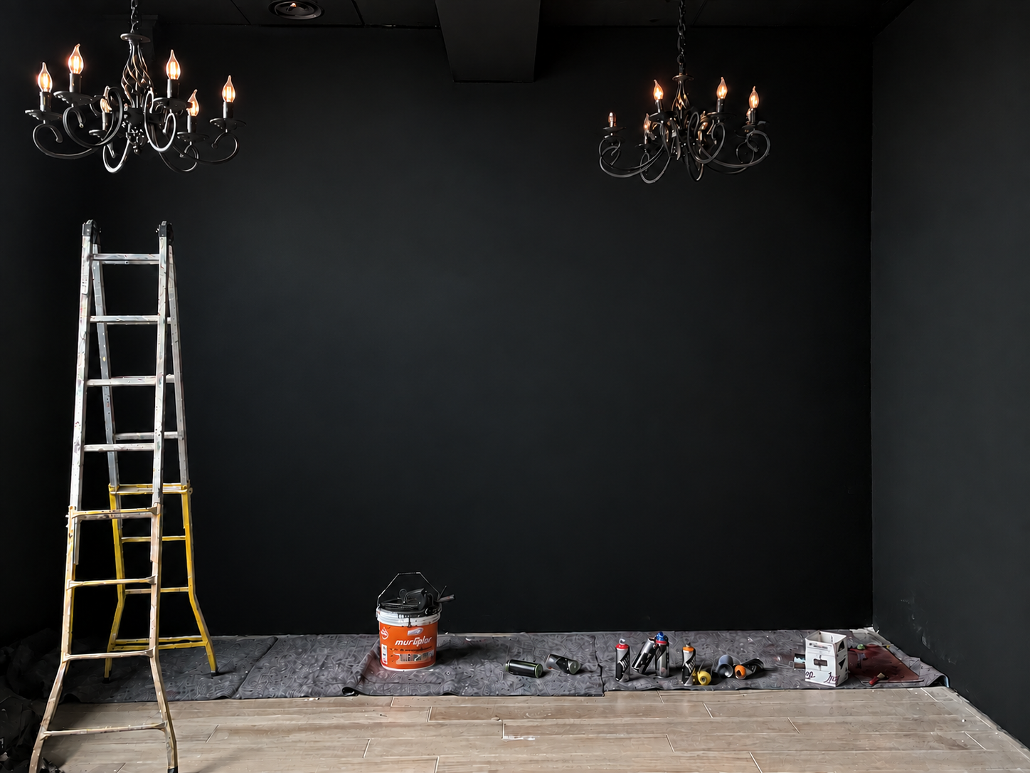 Empty dark room with ladders and paint ready for a mural